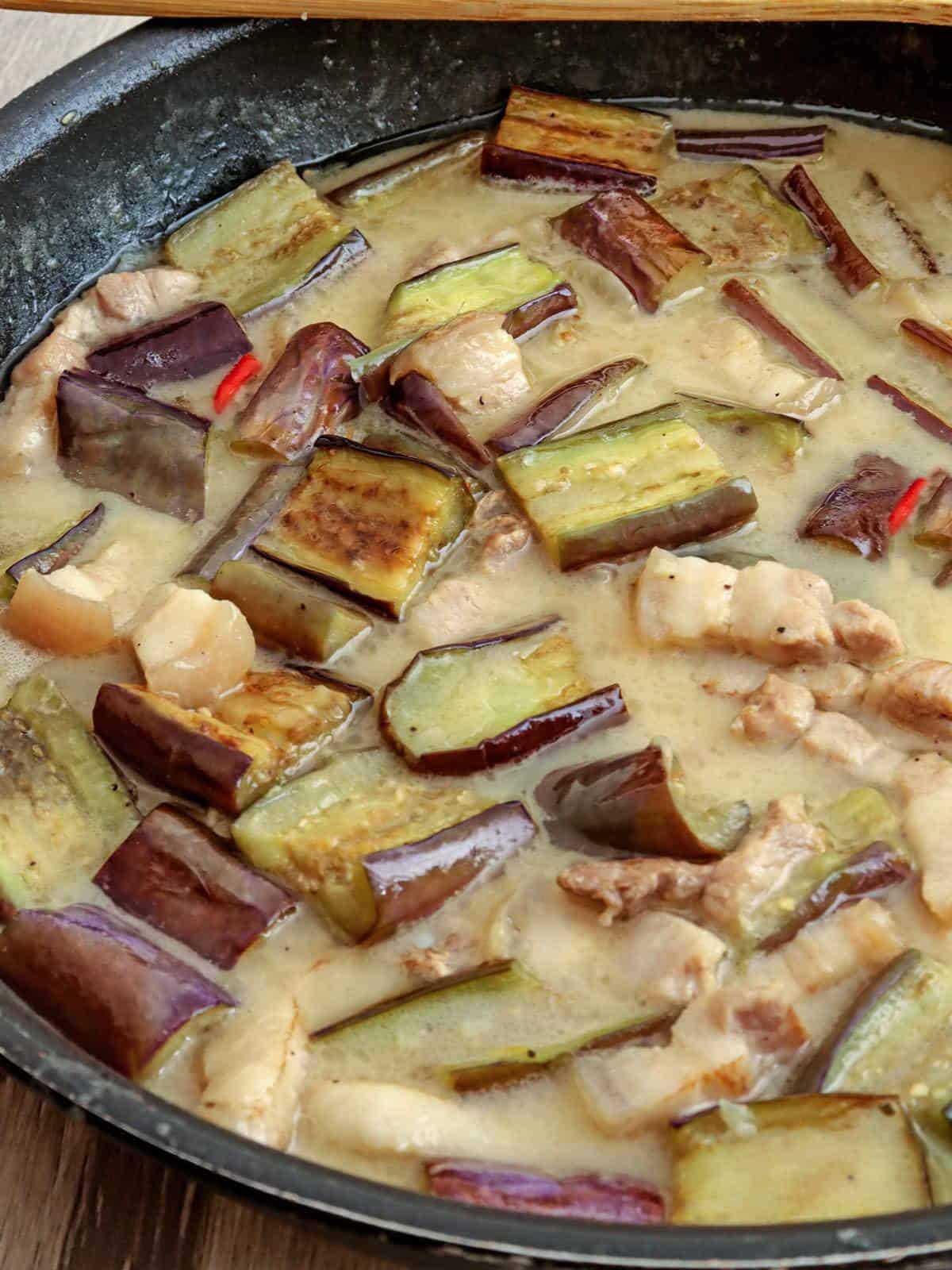 eggplant and pork in coconut sauce in a skillet.