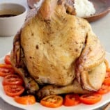 Pinaupong Manok on a white serving platter over sliced tomatoes.